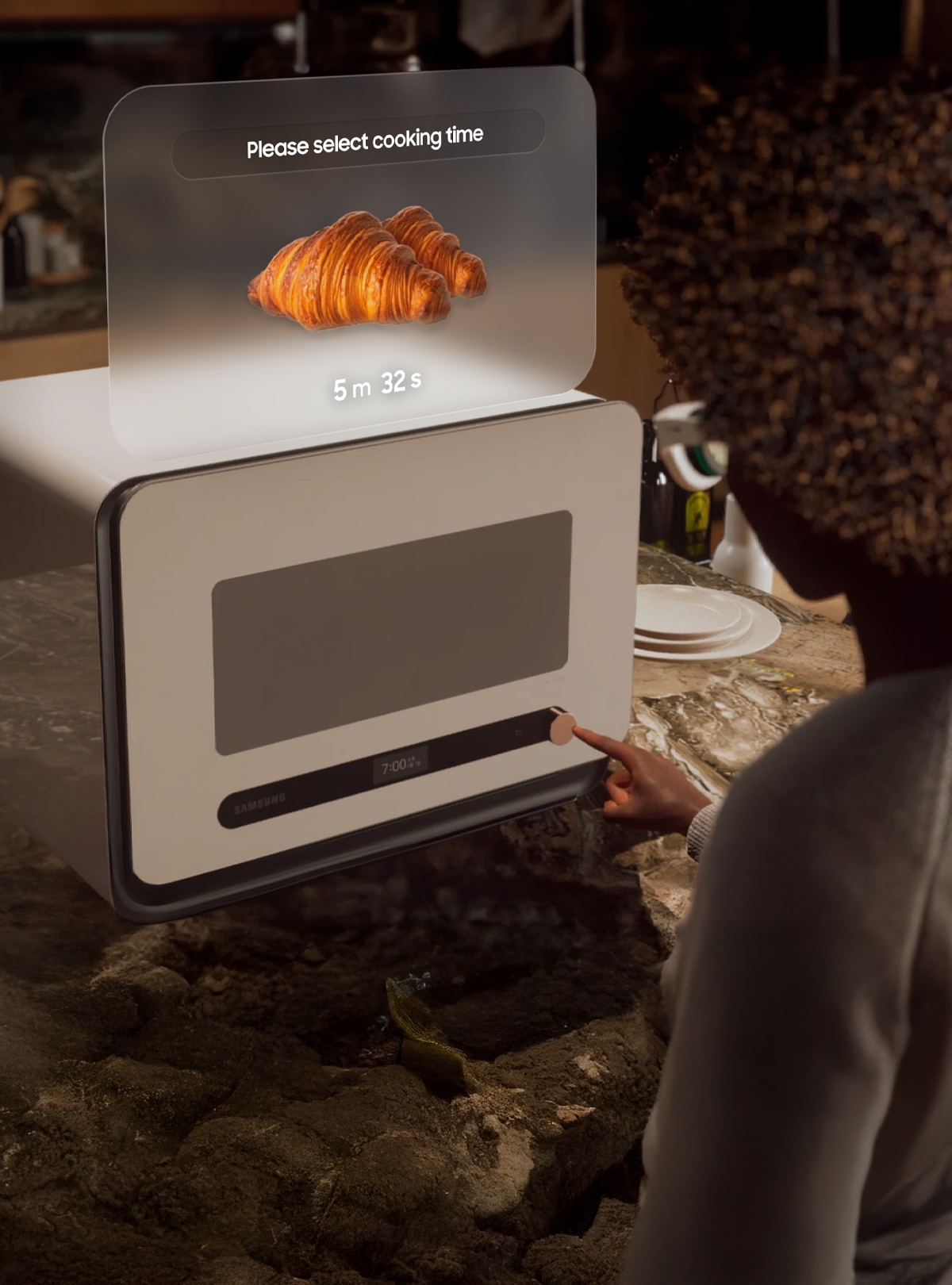 The image shows a curly-haired figure wearing a pair of glasses on the right, looking at the cooking time for a croissant on a virtual panel hovering above the oven. The virtual panel shows an image of a croissant with the words Please select a cooking time and reads five minutes and thirty two seconds below.