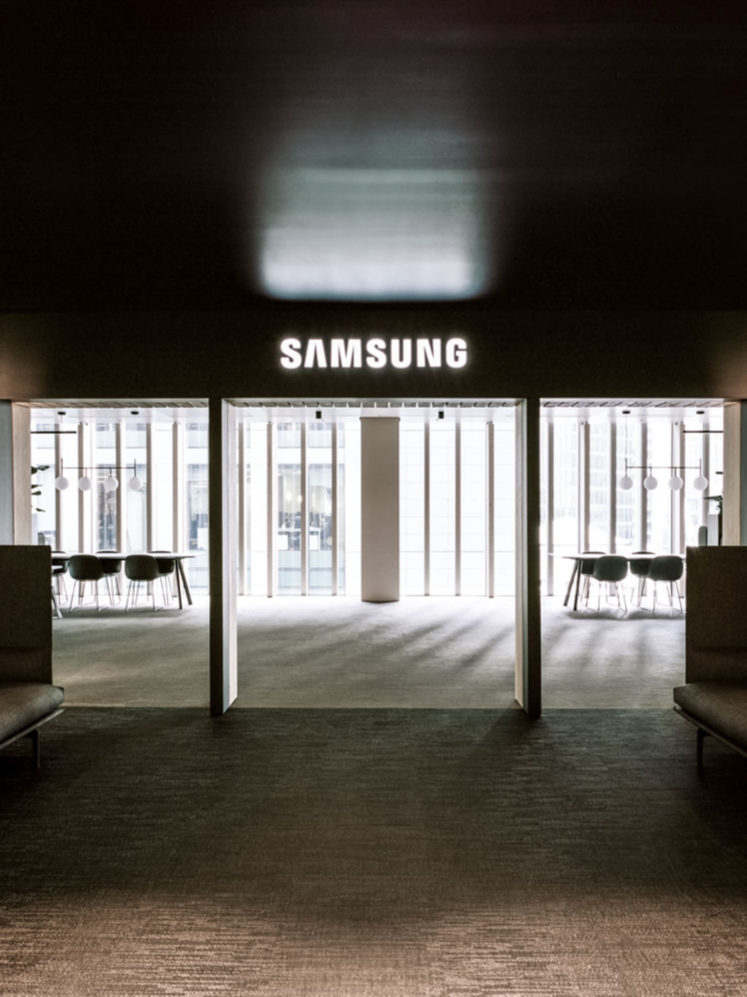 A modern and sophisticated interior space with the Samsung logo brightly illuminated. A harmonious blend of meeting rooms and cozy lounges highlights the clean design.