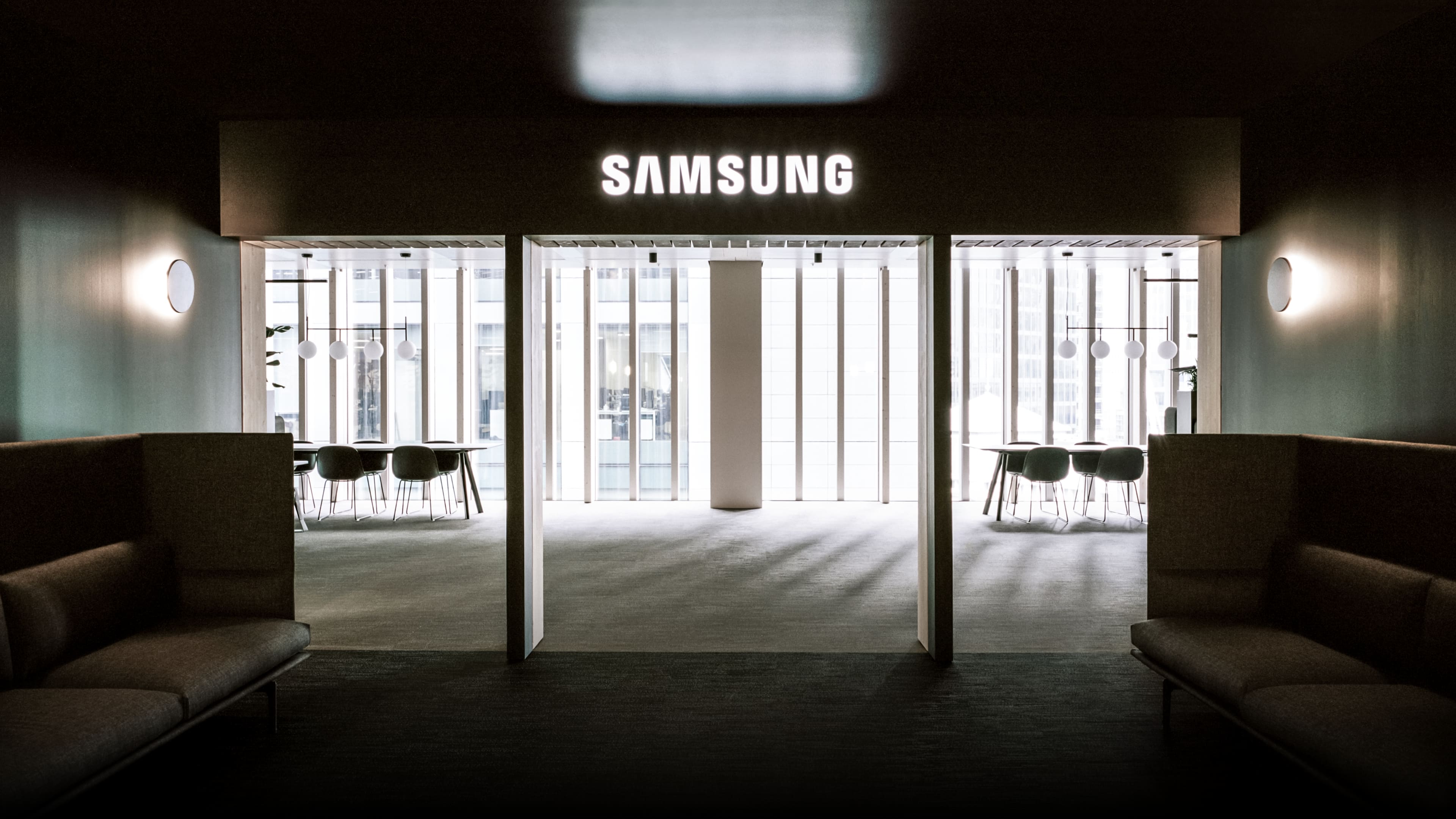 A modern and sophisticated interior space with the Samsung logo brightly illuminated. A harmonious blend of meeting rooms and cozy lounges highlights the clean design.