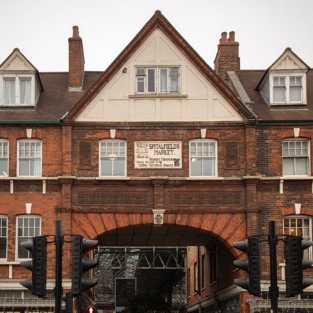 A red-brick building with Victorian architectural charm, featuring a distinctive archway that bridges the past and present