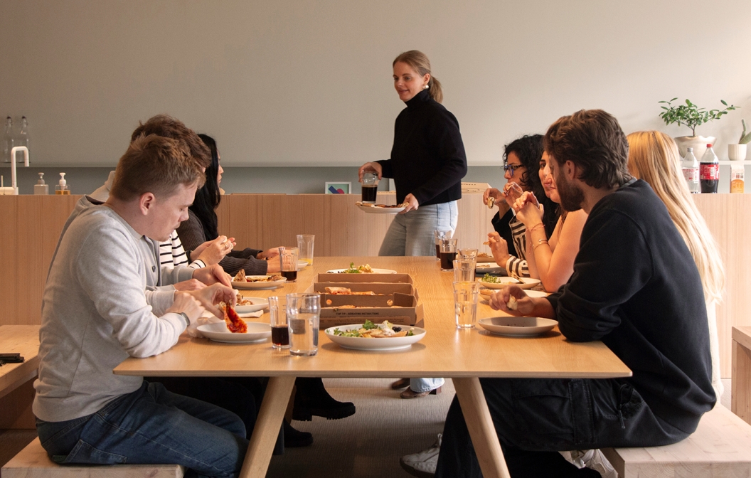 People gathered around a warm wooden table, sharing a meal and engaging in conversation. The scene exudes a sense of comfort and camaraderie.