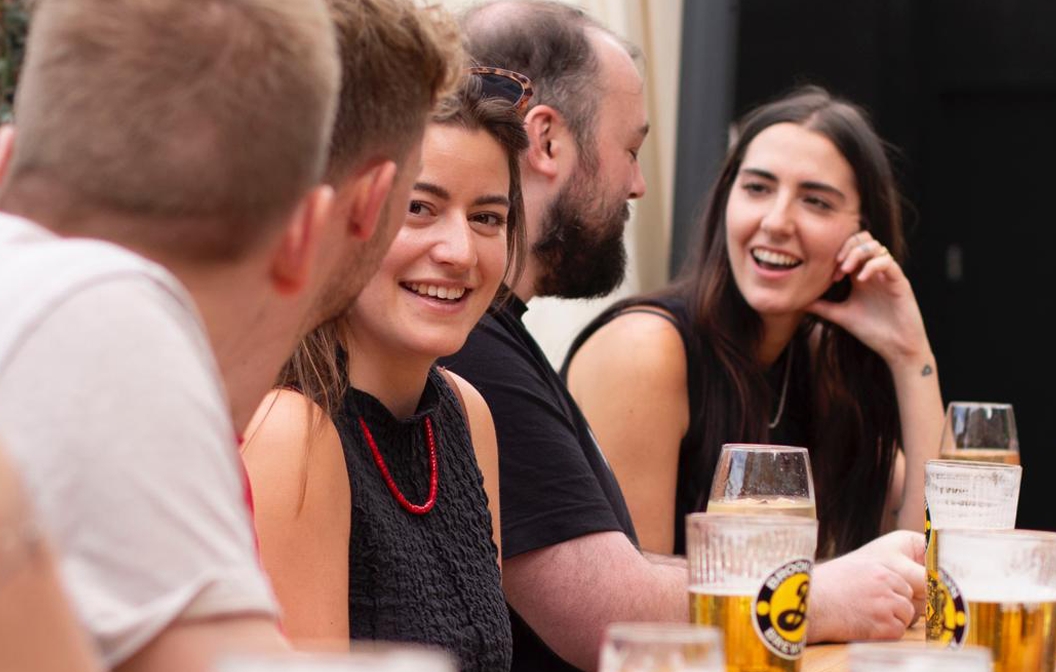 People sharing lively conversations and smiles over glasses of beer, radiating warmth and a vibrant atmosphere.