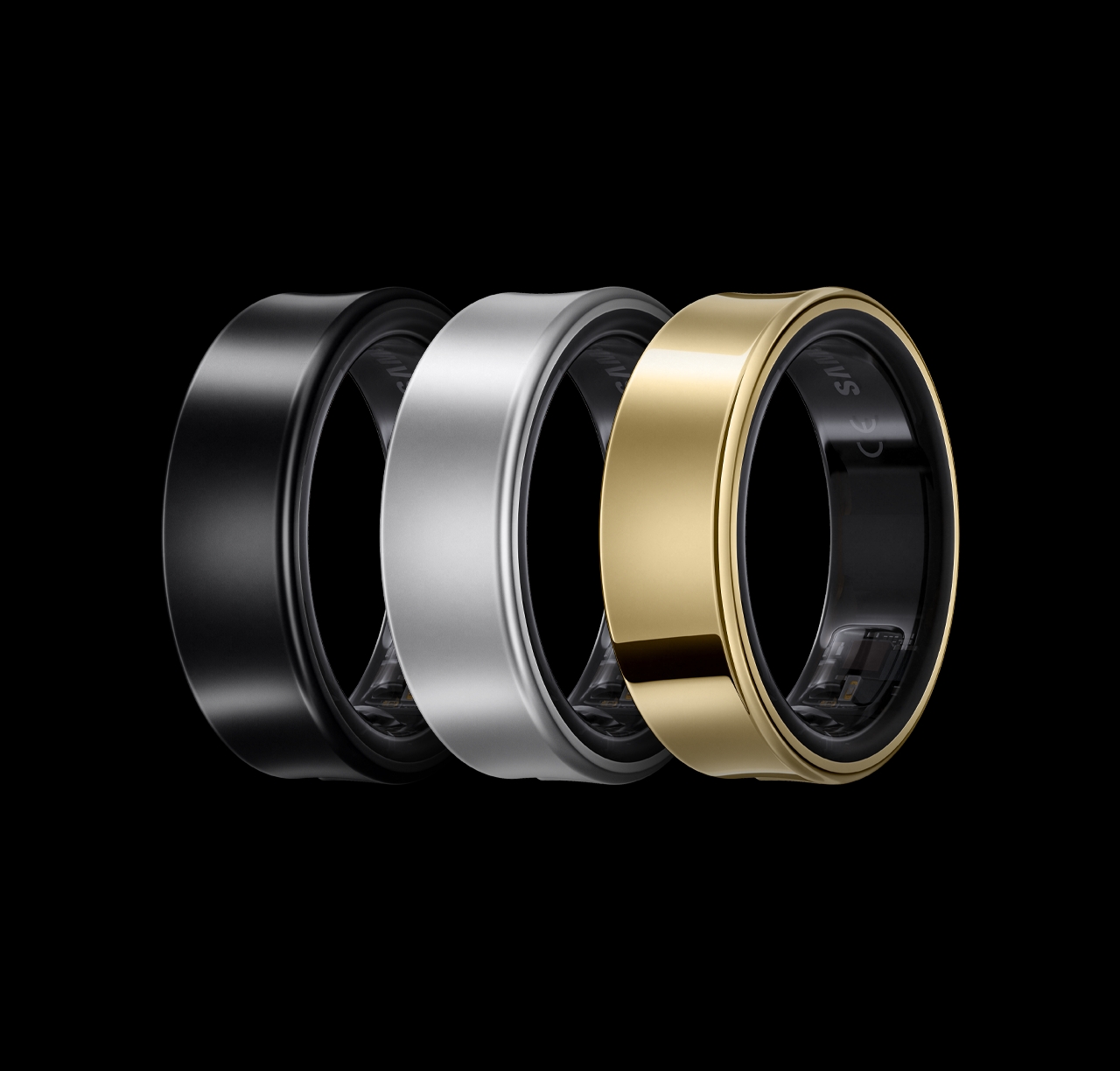 Three colored Galaxy rings lying on their sides, aligned horizontally. The rings are engraved with the alphabet Samsung logo on the inside. From left to right: Titanium Black, Titanium Silver, Titanium Gold.