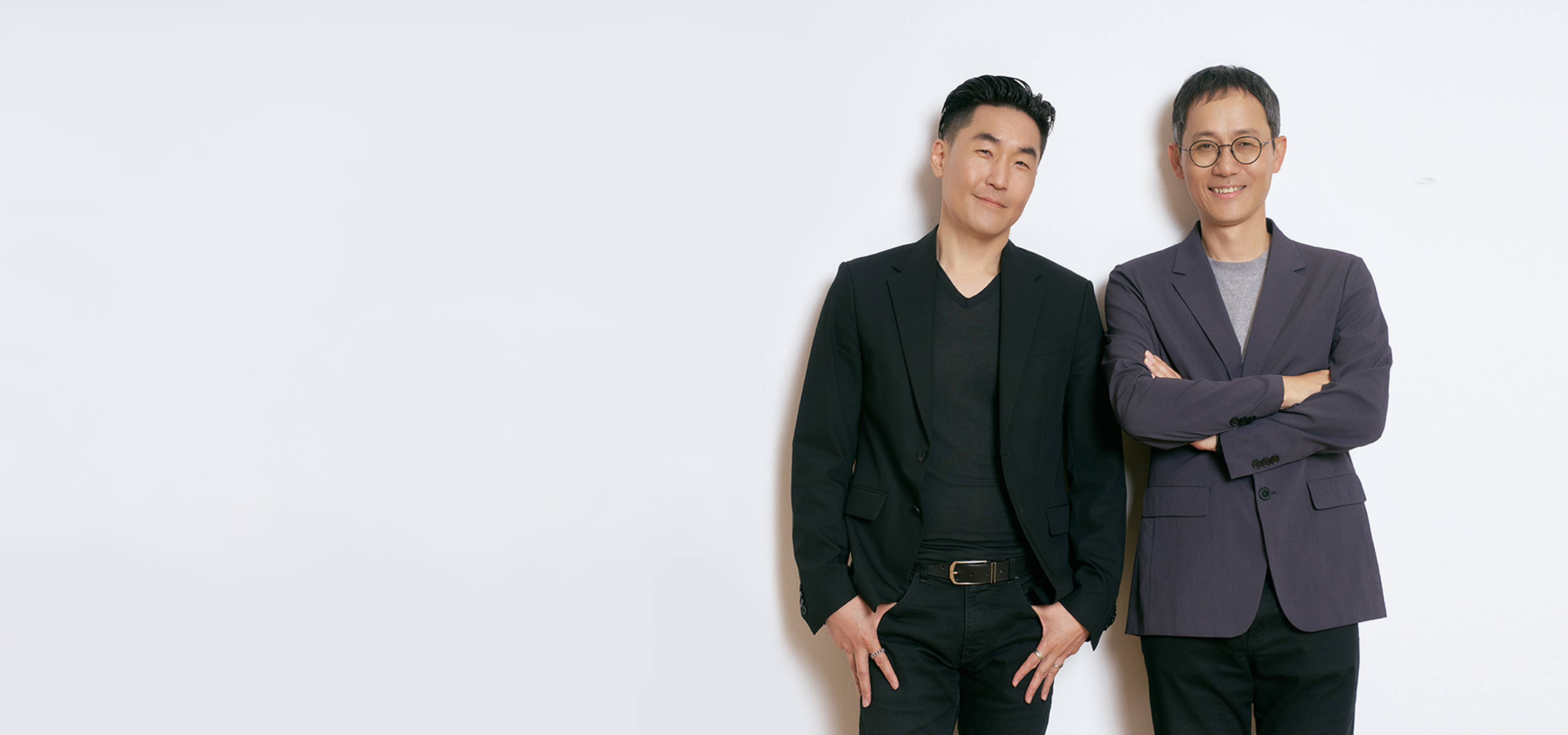 Hubert Lee, Head of Design Team in the MX Division, wearing a black jacket, and Heecheol Yang, UX Team Lead in the MX Division, wearing a gray jacket and glasses, standing side by side and smiling.