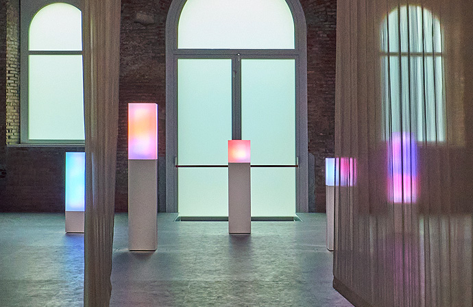 Transparent curtains create a hallway and the colorful light behind it is the image of a diameter inside a cube