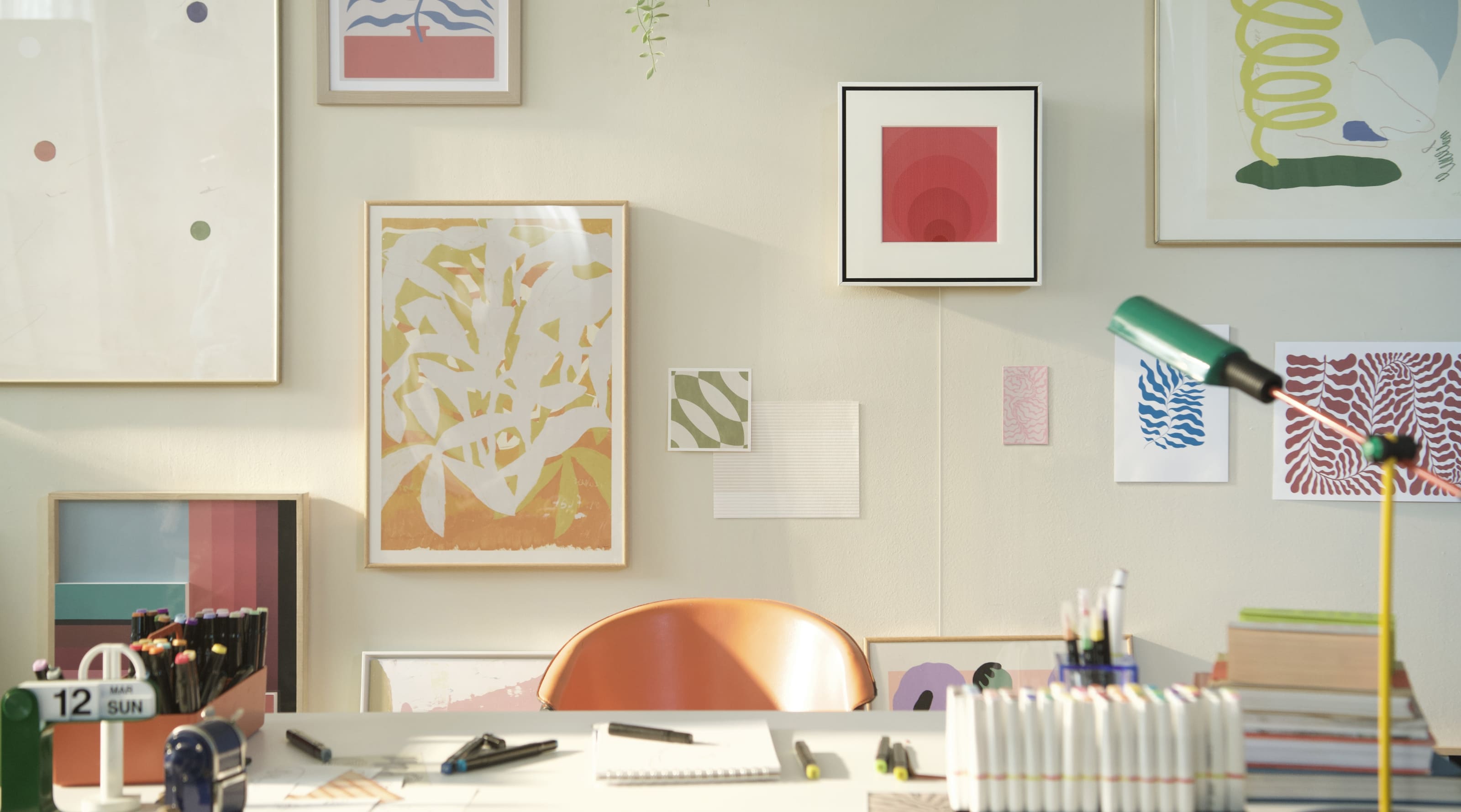 Daytime, bright sunlight illuminates a room that appears to be an artist's studio. A Music Frame hangs harmoniously on one wall alongside a variety of framed paintings. 