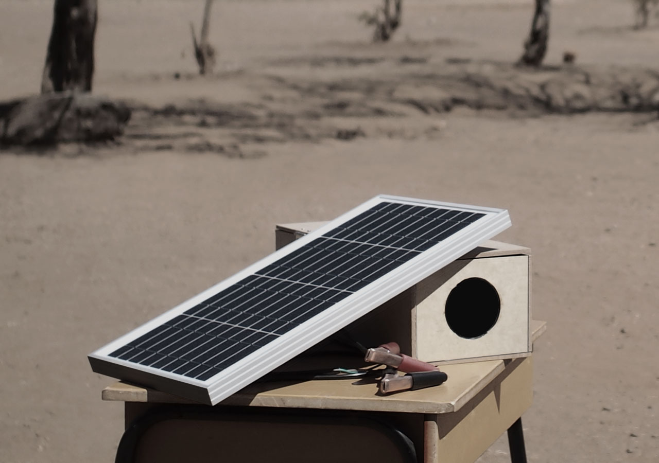 An image shows the shiny projector sitting on the table in the desert.