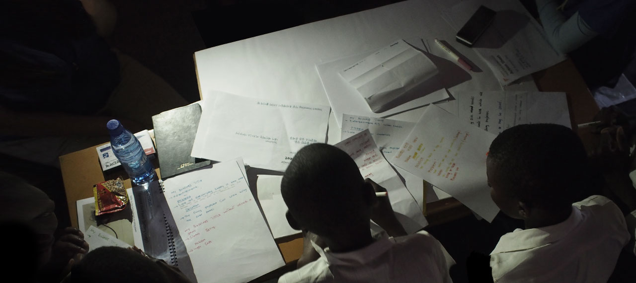 An animation fades-in to show an image of African students practicing their writing during an English class.