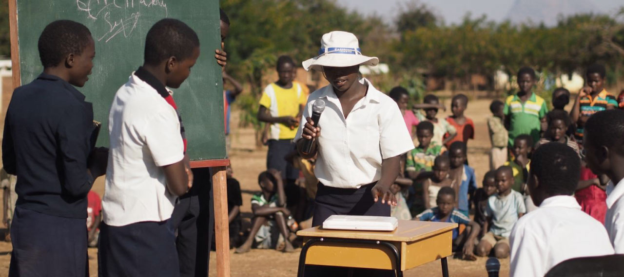 An image shows children acting out a skit