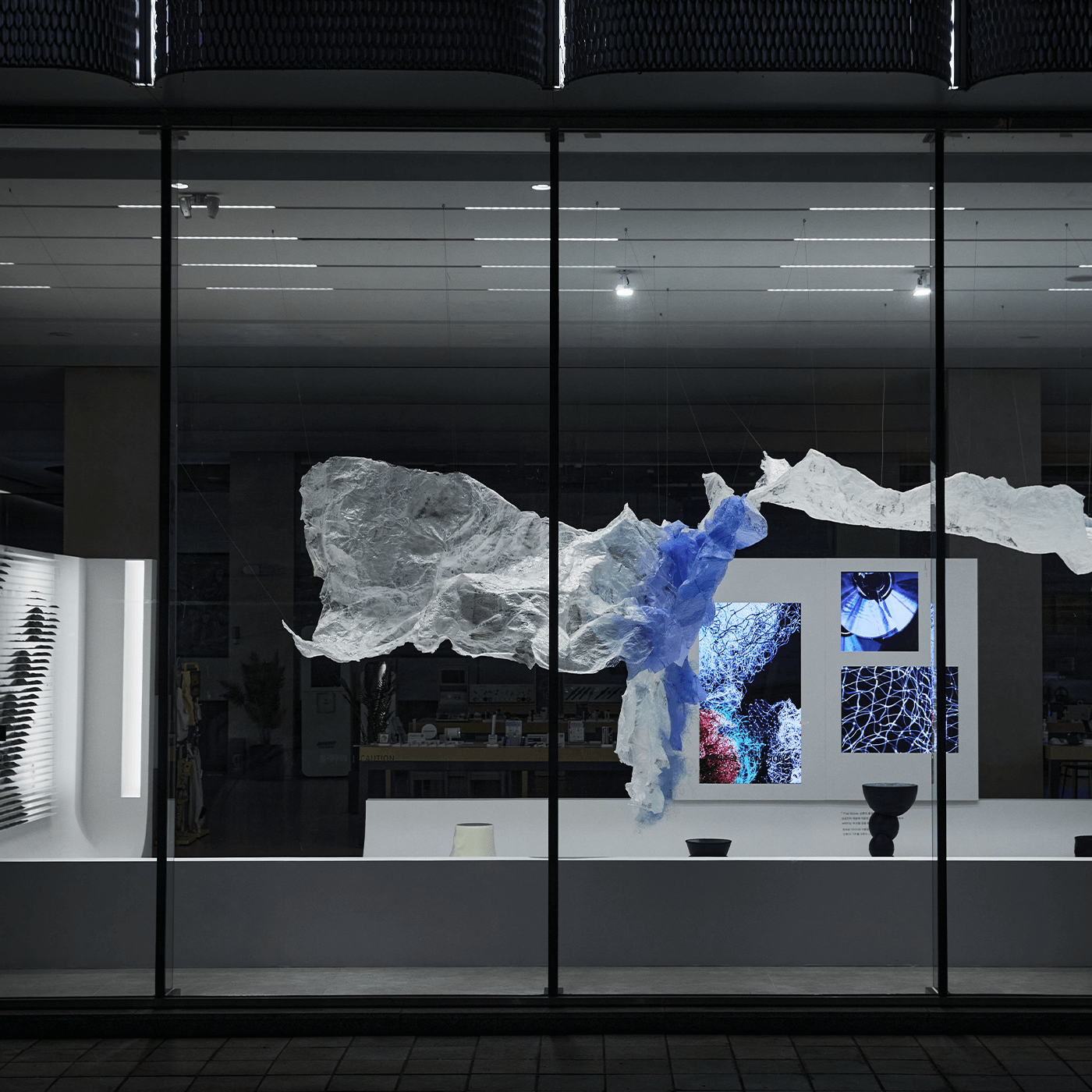 This is an exhibition image of 「The Wave: Creating a Virtuous Cycle」 taken from outside at night.