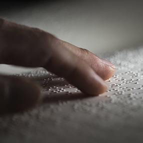 An image of hand reading Braille