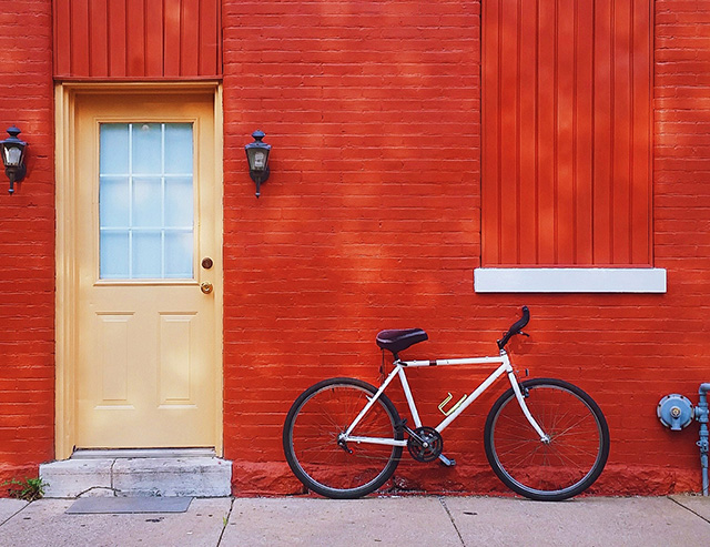 An image of a red wall with a bicycle.