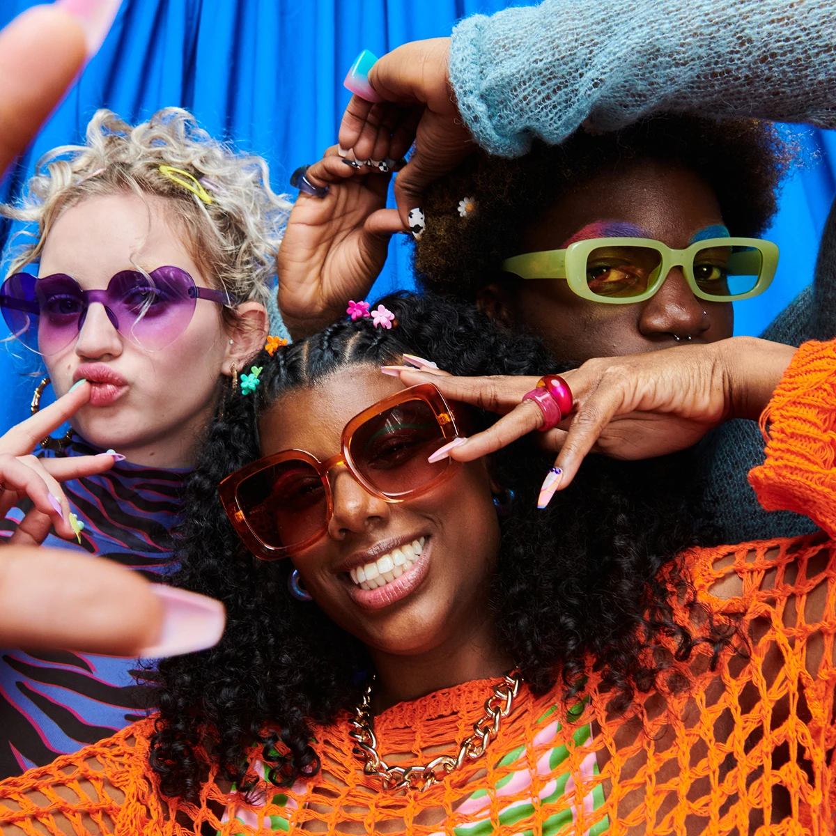 Three people expressing individuality in colorful sunglasses and outfits.